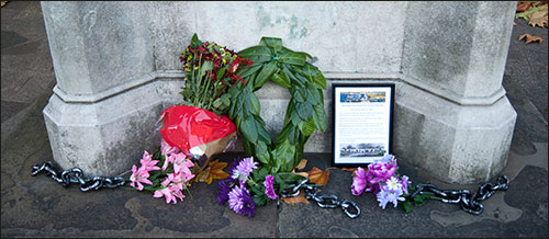 Foto van de voet van het Colston-standbeeld in 2013, met bloemen en kettingen.