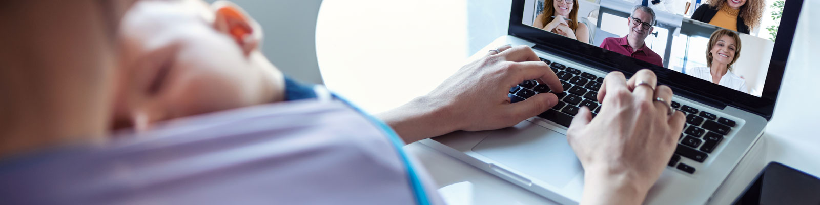 Thuiswerkende moeder met slapende baby in draagzak tijdens online meeting
