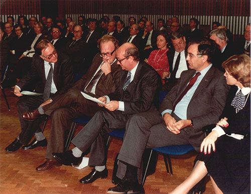 Op de eerste rij in een zaal zijn Leibbrandt, Van Kemenade en De Moor in gesprek. Kremers kijkt toe.