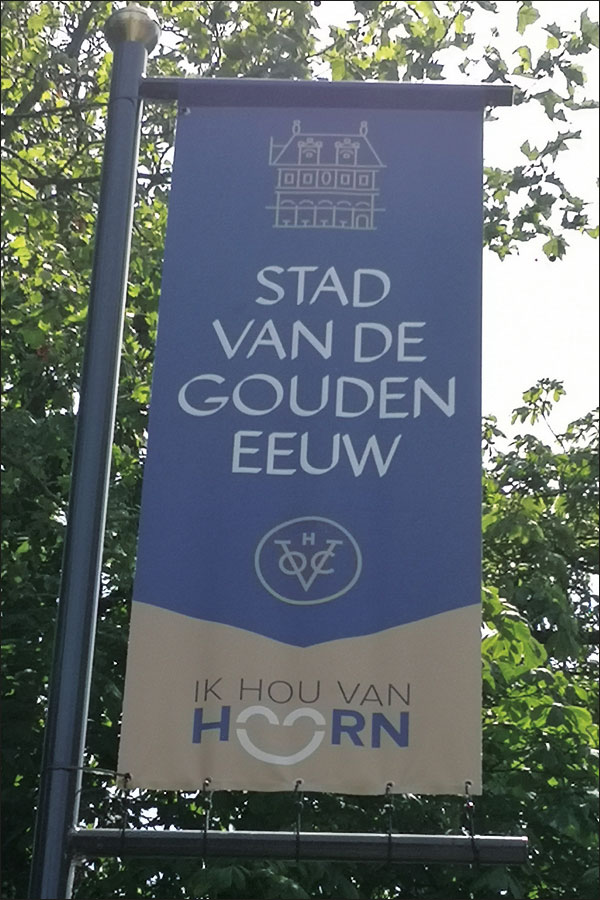 Banier met daarop de tekst Stad van de gouden eeuw, het lovo van de VOC met toegevoegde H, en het kenmerk Ik hou van Hoorn.