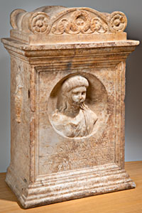 Grafaltaar van Caetennia Pollita: uit een marmeren blok is een steen gehouwen, omrand met uitstekende lijsten en bekroond met bloemmotieven. Op de voorkant is een cirkel uitgehold met daarin een buste van een meisje. Daaronder staat een bijschrift in Romeinse letters.